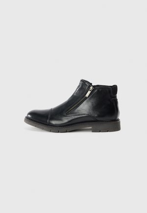 Bottines en cuir noir avec fermetures éclair sur les côtés, design minimaliste, bout arrondi, détails de couture subtils et semelle en caoutchouc texturée basse.