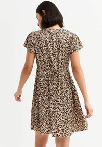 Abito stampato floreale con maniche a soffietto corte, vita arricciata e gonna svasata. Presenta uno sfondo beige con macchie scure.