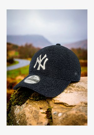 Jaunā laikmeta beisbola cepure tumši zila polā, ar kontrastējošu balto NY logo, noapaļota forma un regulējama siksna. Etiķete redzama uz malām.