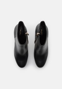 Botines de cuero negro con textura lisa, con cremallera lateral dorada y diseño de punta redondeada. Marca "ALDO" en dorado en el interior.