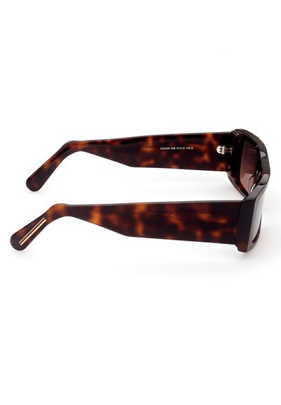 Occhiali da sole tartarugati con montatura quadrata, dotati di lenti scure e tempie allungate e texturizzate con accenti metallici.