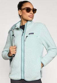 Ελαφρύ γαλάζιο φλις μπουφάν με φερμουάρ, πλαϊνές τσέπες και αντίθετη διακόσμηση. Διαθέτει μικρό λογότυπο στο στήθος και απαλό, υφασμένο φινίρισμα.