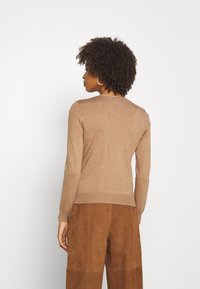 Pull marron à manches longues et à col rond, fabriqué en matériau tricoté doux. Affiche un design ajusté et une taille côtelée.
