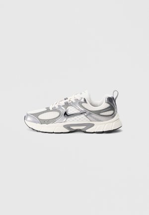 Sneaker argento e bianco con sovrapposizioni in mesh e materiale sintetico, caratterizzata da accenti neri, suola strutturata e lacci di colore chiaro.