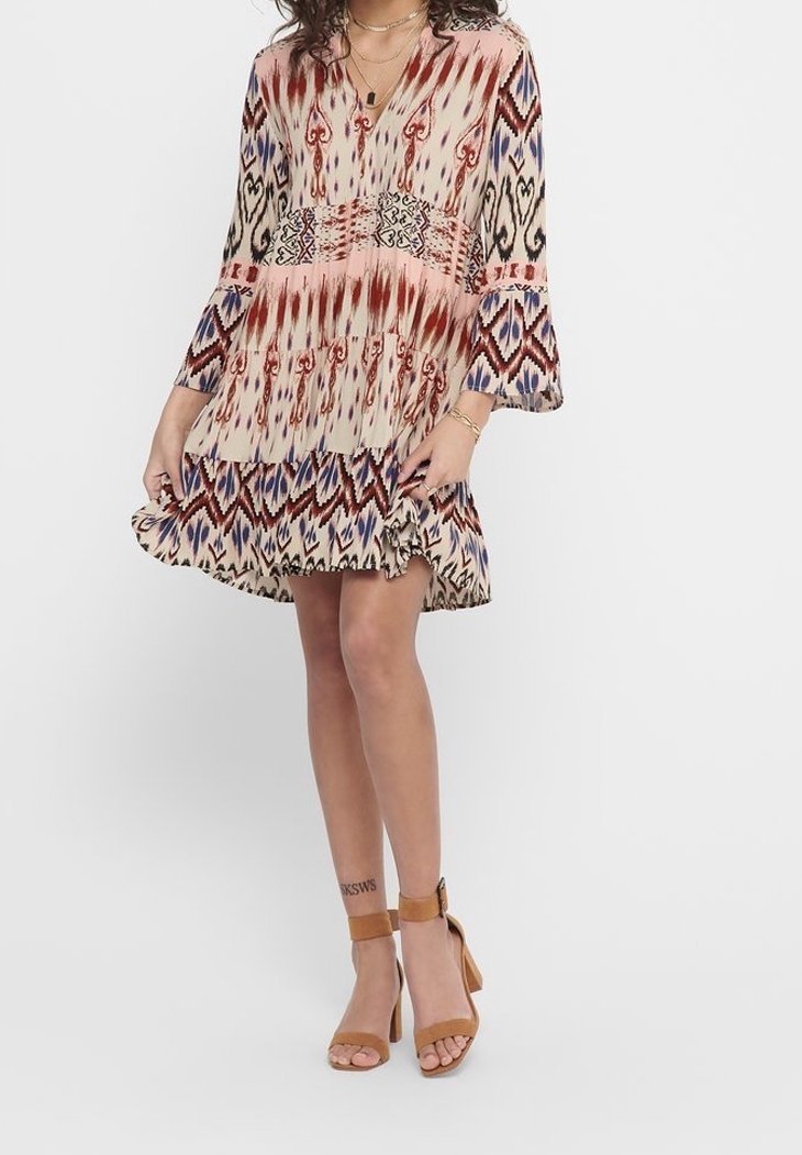 Vestido de estampado floral en beige con acentos rojos y azules. Presenta mangas largas acampanadas, escote en forma de V y un dobladillo con volantes en capas.