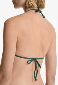 Groene bikinitop met een halternek en verstelbare striksluiting aan de achterkant. Glad textuur en minimalistisch ontwerp.