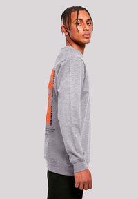 Gray long-sleeve shirt with orange and purple text graphic on the back. Smooth texture with ribbed cuffs and hem. Regular fit.