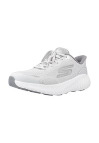 Zapatilla deportiva ligera de color gris con parte superior de malla, puntera redonda, cuello acolchado y suela blanca texturizada con un patrón de olas.