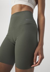 Wysokowysokie szorty rowerowe Nike w oliwkowej zieleni, wykonane z gładkiego, elastycznego materiału, z subtelnym logo i dopasowanym krojem.