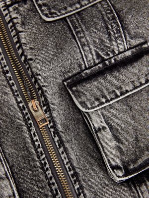 Jachetă din denim alb-negru cu un fermoar auriu, cusături vizibile și două buzunare frontale cu clapetă, evidențiind un material texturat.