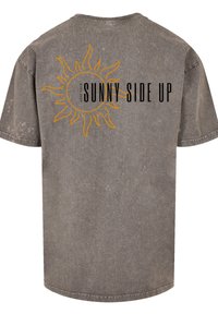 Gray, oversized T-shirt with short sleeves. Features a sun graphic and the text "KEEP YOUR SUNNY SIDE UP" in black and orange.