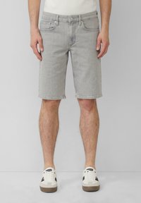 Shorts en denim gris avec une coupe droite, design à cinq poches, et un ourlet juste au-dessus du genou. Associés à des baskets blanches et grises.