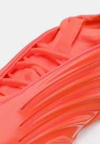 Ljust orange sneaker med texturerat tyg, matchande snören och glänsande sidodesign detaljer.