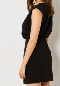 Schwarzes ärmelloses Kleid mit lockerem Oberteil und taillierter Taille, das eine glatte Textur und eine klassische A-Linien-Silhouette aufweist.