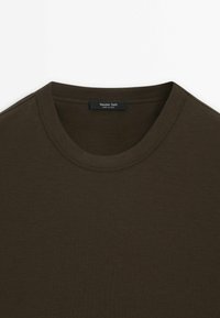 T-shirt marrone scuro con colletto rotondo, texture liscia e dettagli cuciti. L'etichetta riporta "Massimo Dutti."