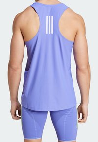 Canottiera sportiva viola con design a racerback, caratterizzata da tre strisce verticali bianche sul retro. Tessuto morbido e leggero.