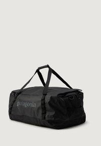 Sort Patagonia duffel taske med dobbelt håndtag og skulderremme, vist på en neutral baggrund.