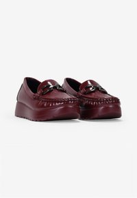 Mocassini in pelle bordeaux con texture a cuciture in rilievo, suola platform spessa e dettaglio in metallo nella parte anteriore.