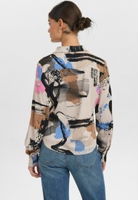 Bunt gemusterte Seidenbluse mit abstrakten Mustern in Rosa, Blau, Schwarz und Braun; sie verfügt über einen Hemdkragen und knöpfbare Manschetten.