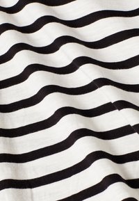 Tela a rayas en blanco y negro con líneas onduladas, que presenta una textura suave. Las rayas varían en ancho sobre un fondo ligero.
