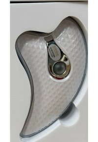 Wygięte białe urządzenie z teksturowanym wzorem diamentowym, srebrnymi akcentami i centralnym przyciskiem. Zapakowane w białą, formowaną wkładkę z pianki.