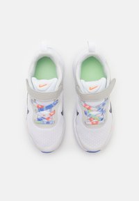 Zapatillas de malla blancas con acentos grises, cordones de colores en azul, rosa y verde, y una plantilla verde claro. Logo de Nike en la lengüeta.