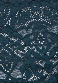 Donkerblauwe kantstof met intricat bloemmotieven, voorzien van opengewerkte details en een textuurrijke oppervlakt.