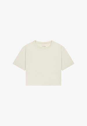 Beiges, kurzgeschnittenes T-Shirt aus Baumwolle mit kurzen Ärmeln und Rundhalsausschnitt, flach auf weißem Hintergrund liegend.