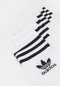 Fehér sportzoknik fekete csíkokkal a szélén és fekete Adidas logóval. Ráncolt textúra; öt pár sorban elhelyezve.