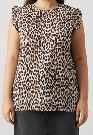 Kobieta ubrana w bezrękawową bluzkę w panterkę z falbanami na ramionach i ciemną spódnicę na jednolitym tle.