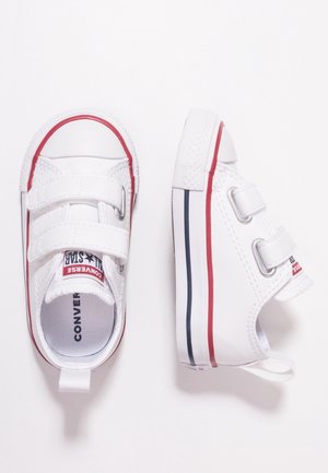 Baskets blanches pour tout-petit avec des rayures rouges et bleues, deux bandes velcro et un marquage "Converse" sur la languette, vues de dessus et de côté.