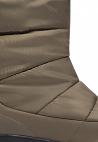 Khaki zateplená bota s texturovaným, prošívaným designem a kontrastní černou podešví, navržená pro teplo a pohodlí v chladném počasí.