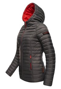 Veste grise isolée avec capuche, doublure rouge, texture matelassée, deux poches zippées et logo sur la manche. Fermeture éclair rehaussée de rouge.