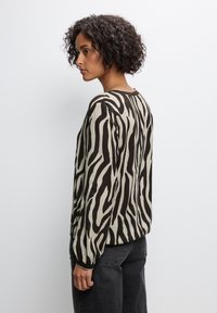 Langarmshirt in Beige mit schwarzen Zebra-Streifen, aus glattem Stoff. Mit Rundhalsausschnitt und leicht gerafften Ärmeln.