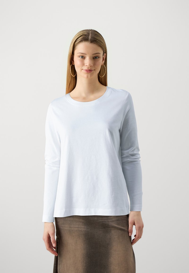 Camisa de manga larga azul claro en algodón suave, con cuello redondo y un ajuste relajado, combinada con una falda marrón.