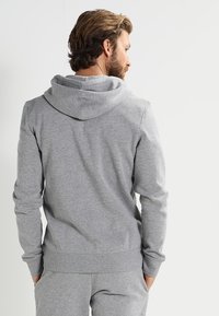 Grå hoodie gjord av mjuk och bekväm tyg. Har en justerbar huva, ribbade ärmar och midja, med en avslappnad passform.