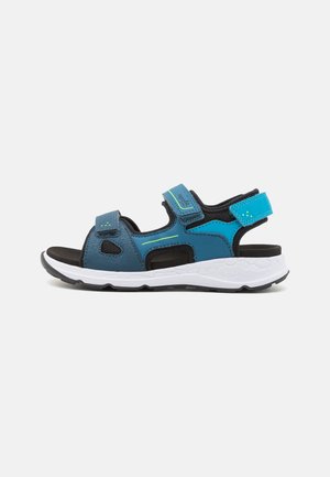 Sporty blå og sorte åbne sandal med justerbare velcroremme og en tyk hvid polstret sål.