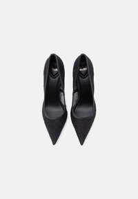 Chaussures à talons hauts en dentelle noire avec un bout pointu et une doublure intérieure douce. Caractérisées par un motif texturé et un design élégant.