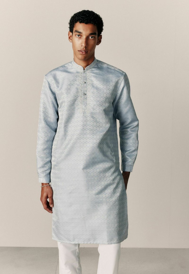 Hellblaues Kurta aus glattem Stoff mit einem dezenten Diamantmuster, mit Stehkragen und Knöpfen, getragen mit weißer Hose.