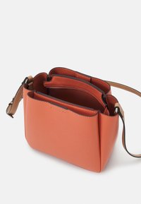 Piccola borsa a tracolla in pelle arancione con una superficie testurizzata, dotata di una tracolla marrone e diversi scomparti interni. Linee pulite e cuciture sottili.