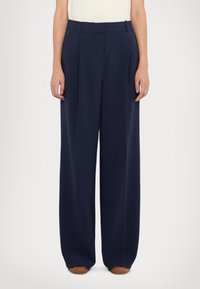 Pantalons larges navy en tissu léger, dotés d'une taille haute, de plis et de poches latérales. Texture lisse et coupe ajustée.