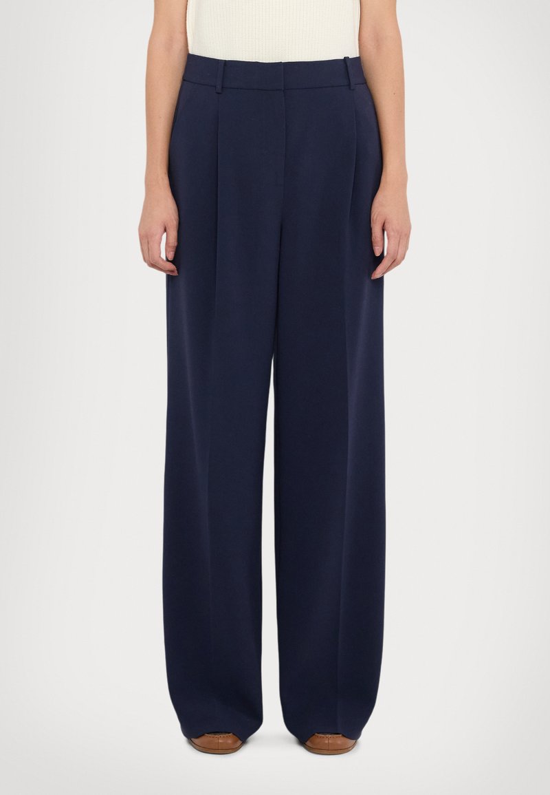Pantalons larges navy en tissu léger, dotés d'une taille haute, de plis et de poches latérales. Texture lisse et coupe ajustée.