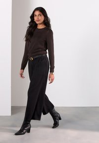 Brun langærmet sweater, sorte high-waist bukser med vide ben, sorte ankelstøvler, sort bælte med guldlås, tekstureret stof, minimalistisk design.