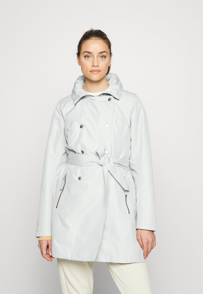 Abrigo trench de color gris claro con diseño de doble botonadura, gran cuello, cintura ceñida con cinturón y bolsillos laterales con cremallera. Tejido suave y resistente al agua.