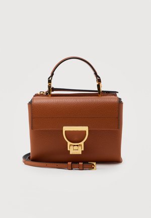 Καφέ δερμάτινη γυναικεία τσάντα με χρυσό μεταλλικό κούμπωμα, επάνω χερούλι και ρυθμιζόμενο ιμάντα ώμου σε απλό ανοιχτό φόντο.