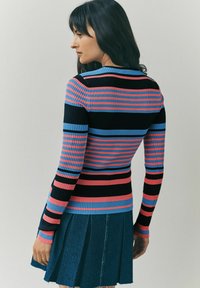 Pull à côtes ajusté avec des rayures horizontales noires, roses et bleues. Présente des manches longues, un col rond et un tissu texturé.