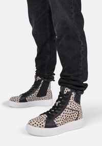 Beige High-Top-Sneaker mit schwarzen Leopardenflecken, ausgestattet mit einem schwarzen Lederakzent und weißer Gummisohle. Strukturiertes Obermaterial und Schnürverschluss.