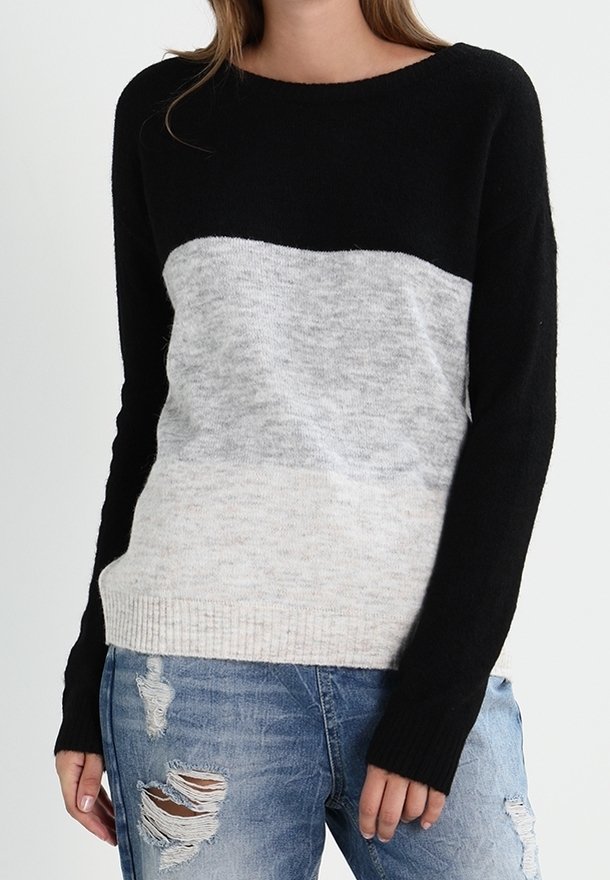 Czarny i szary sweter w blokowe kolory o miękkim, teksturowanym wykończeniu; posiada długie rękawy i prążkowany dół, noszony z postrzępionymi niebieskimi dżinsami.