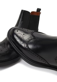 Botas Chelsea de cuero negro con detalles de perforación, acabado liso, paneles laterales elásticos y punta redonda con una suela texturizada.