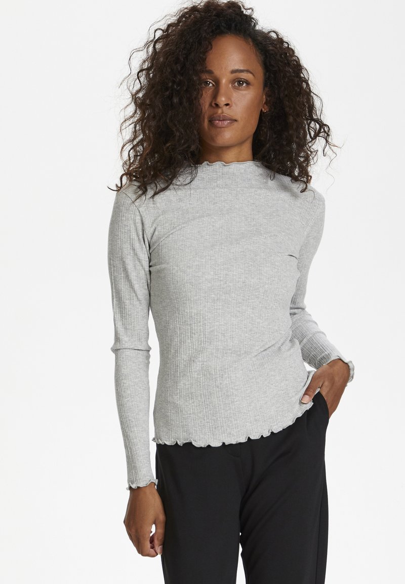 Graues, geripptes Langarmoberteil mit gewelltem Ausschnitt und Bündchen. Figurbetontes Design mit glatter Textur. Kombiniert mit schwarzen Hosen.